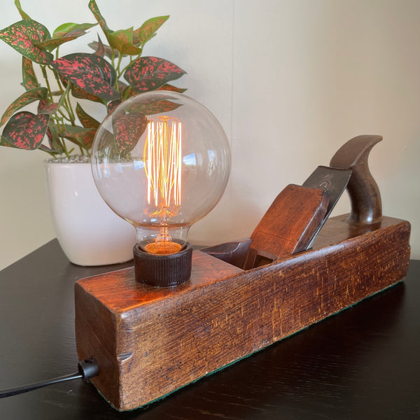 Authentic carpenters plane upcycled into unique lamp with edison bulb, lit.