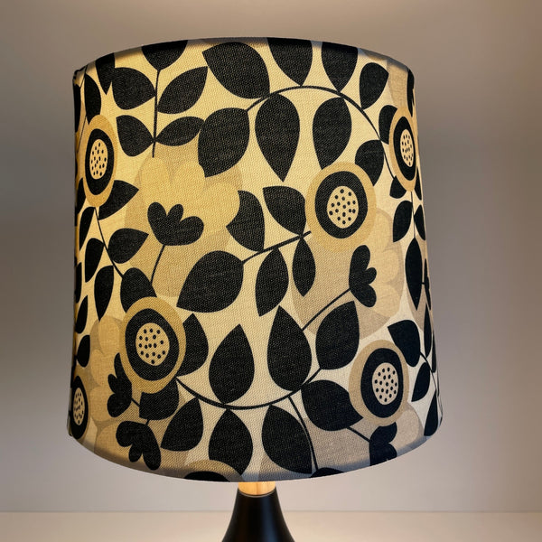 Handcrafted lampshade by shades at grays with graphic bloom fabric, lit.