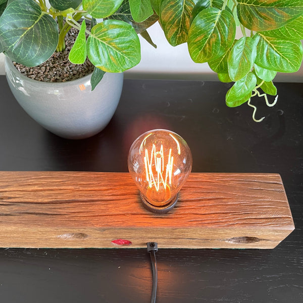 Wood table lamp crafted by shades at grays from telegraph cross piece, lit, close up of edison bulb and wood grain.
