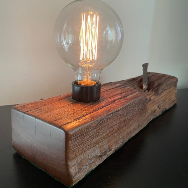 Upcycled wood table lamp from origianl wharf timber, vintage nail and replica edison bulb, lit, smooth end grain, handcrafted by shades at grays.