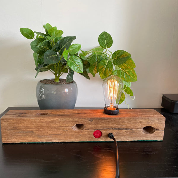 Wood table lamp crafted by shades at grays from telegraph cross piece, lit, back view.