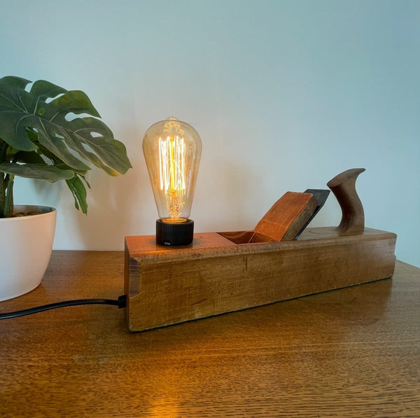 Wood table lamp upcycled by shades at grays from authentic carpenters plane with replica edison bulb, lit, front view.