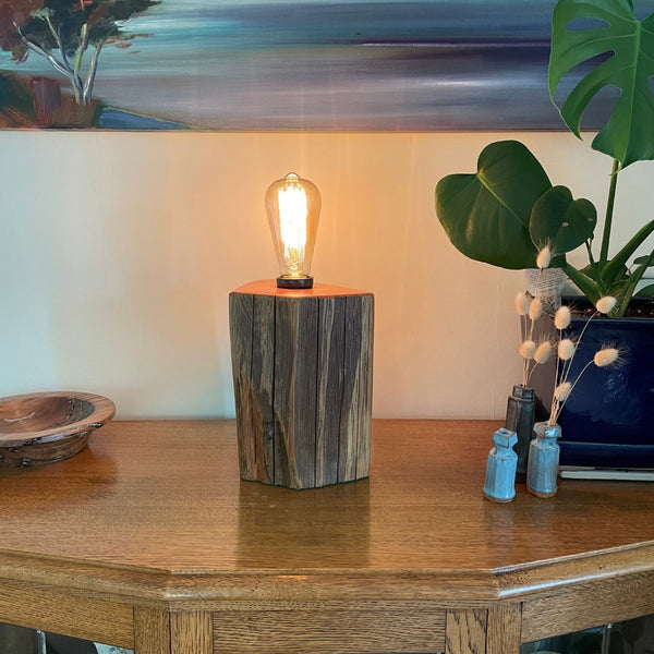 Timber table lamp, polished totara grain with original iron staples and lit edison light bulb.