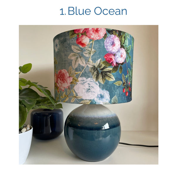 Blue ocean fabric lampshade on blue ceramic base, unlit, by shades at grays.