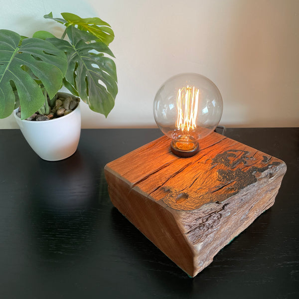 Unique wood table lamp crafted by shades at grays from 100 year old reclaimed wharf timber, lit.