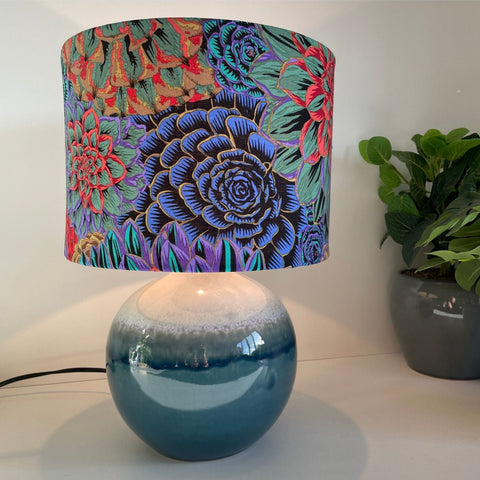 House Leeks Dark fabric lampshade on blue ceramic base, lit, by shades at grays.