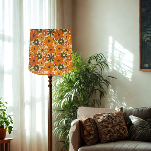 Large tapered lampshade by shades at grays in mid century flower power fabric, on floor stand in lounge setting.
