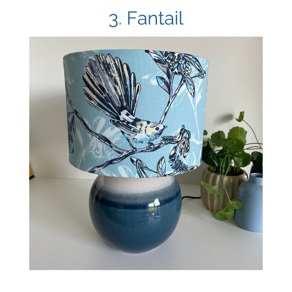 Fantail fabric lampshade on blue ceramic base, unlit, by shades at grays.