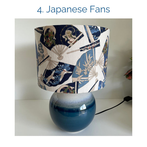 Japanese fans fabric lampshade on blue ceramic base, unlit, by shades at grays.