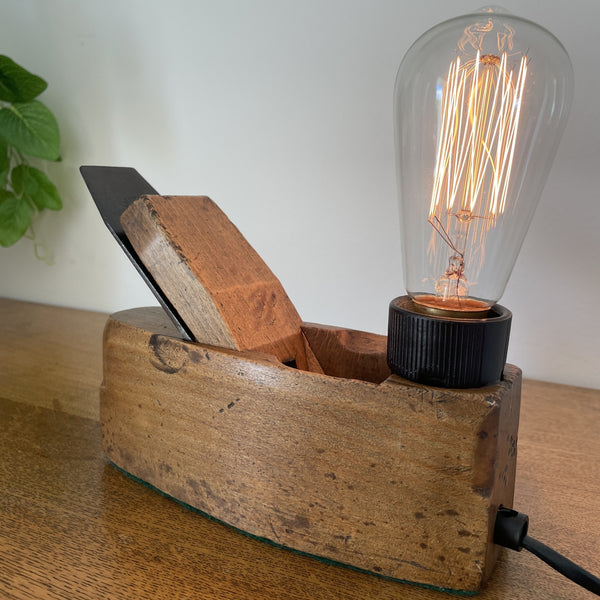 Authentic carpenters' plane upcycled into wood table lamp with edison bulb, lit, crafted by shades at grays, warm honey beech wood, polished with bees wax.