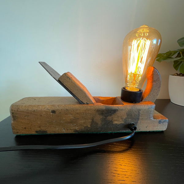 Authentic carpenters plane upcycled by shades at graysinto wood lamp with edison lamp, lit, back view with black lead.