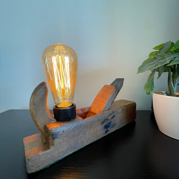Authentic carpenters plane upcycled into wood lamp with edison lamp, lit, front view.