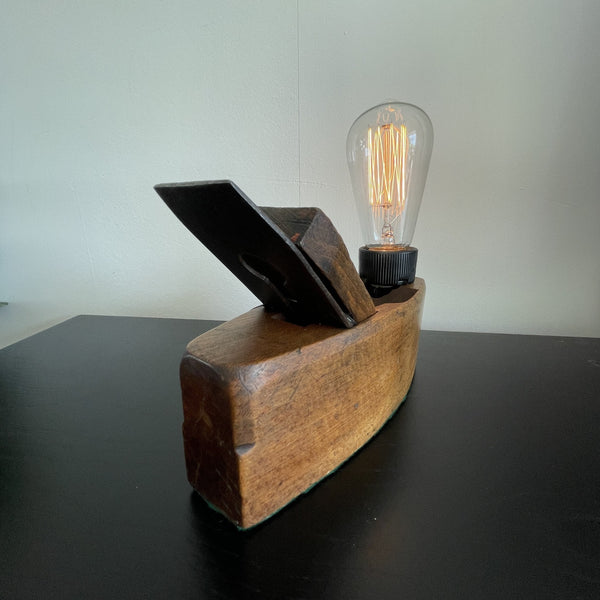 Authentic carpenters plane upcycled to wood table lamp with edison bulb, lit, crafted by shades at grays, back and side view.