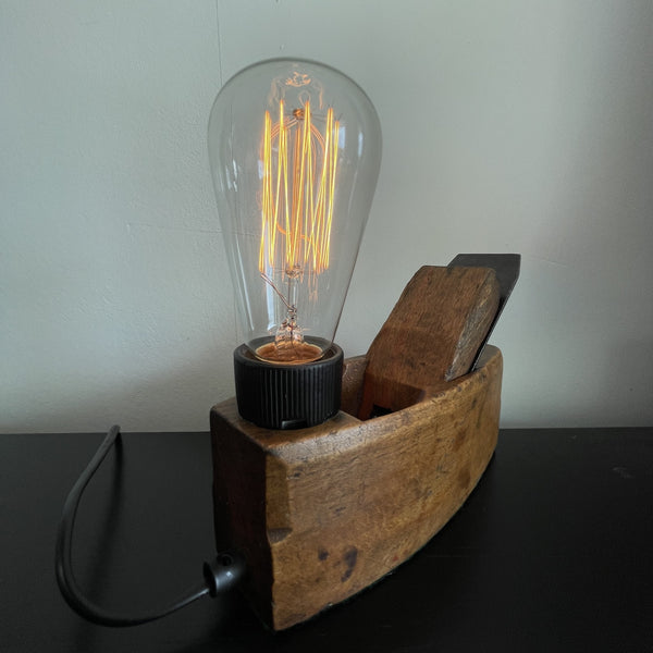 Authentic carpenters plane upcycled to wood table lamp with edison bulb, lit, crafted by shades at grays, back view with black lead.