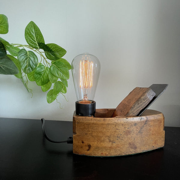 Authentic carpenters plane upcycled to wood table lamp with edison bulb, lit, crafted by shades at grays, front view.