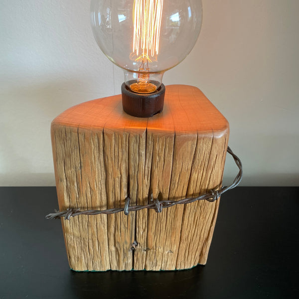 Authentic tōtara fence post upcycled by shades at grays to unique lamp with edison bulb, lit, polished smooth top grain.