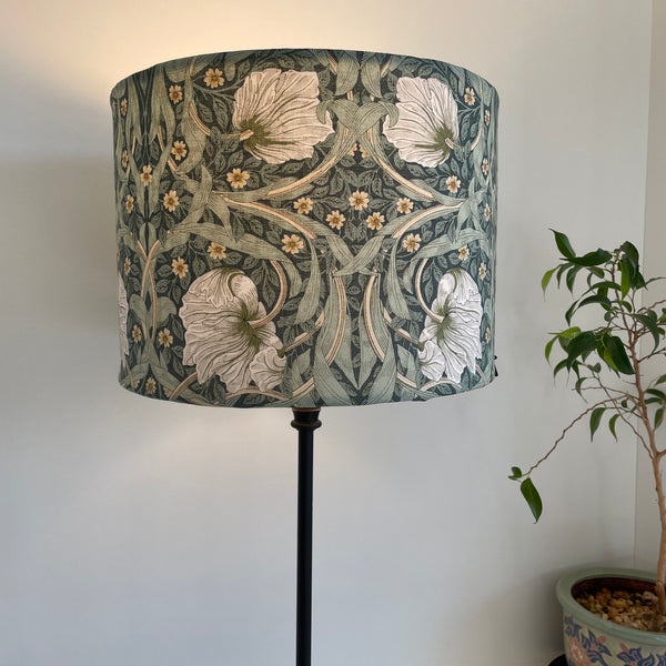 Bespoke medium size drum lamp shade with William Morris Pimpernel Olive fabric, lit, on black lamp base by shades at grays nz.