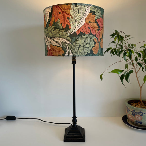 Bespoke medium drum  light shade, with Morris and Co Acanthus Autumn fabric, lit, on black lamp base, by shades at grays nz