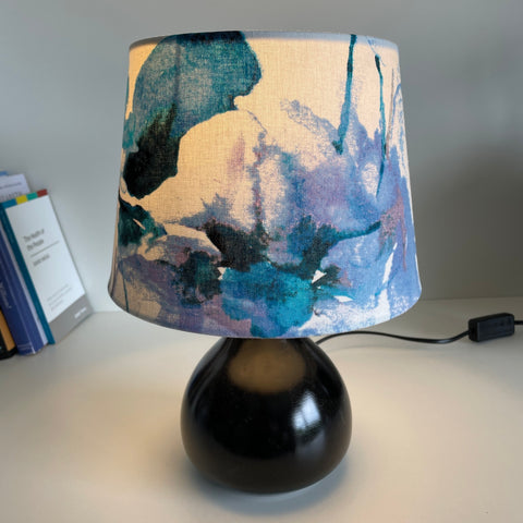 Blues and purples on a clean white background of this watercolour fabric lampshade by shades at grays, lit.