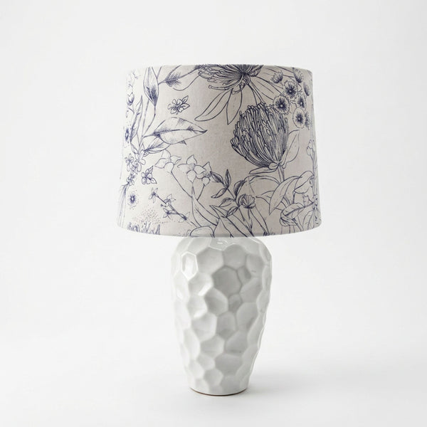 Botanical print lampshade handcrafted by shades at grays, on medium white textured ceramic base, unlit.