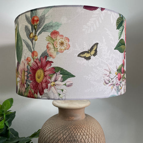 Butterfly and spring hedgerow flowers on a grey and white background, fabric lampshade, lit on terracotta base by shades at grays
