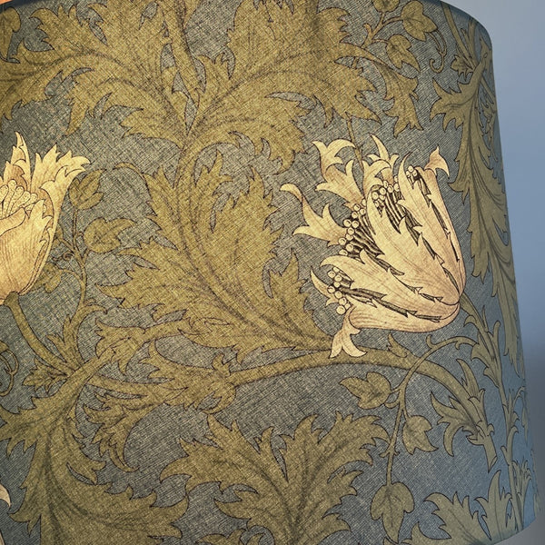 Close up of William Morris Anemone cream fabric on handcrafted lampshade, lit, by shades at grays.