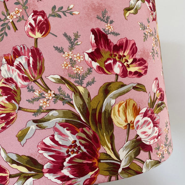 lose up of tulip bouquet fabric with mid pink background and red tulips.
