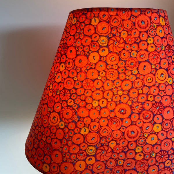 Close up, Large lamp shade handcrafted by shades at grays in nz with Kaffe Fassett button mosaic ornage fabric, lit.
