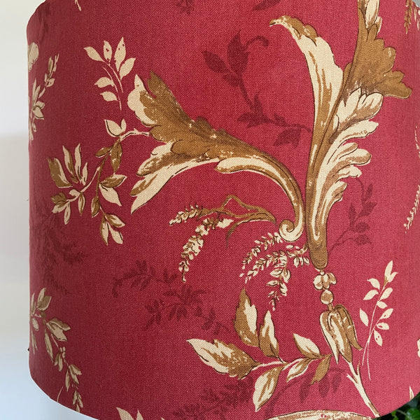 Close up of Large drum fabirc lamp shade made in nz by shades at grays, unlit, gold foliage on red print.