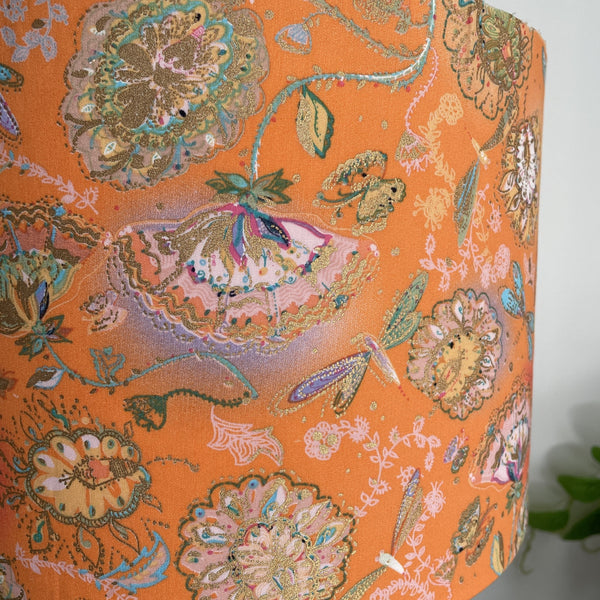 Close up of delicate dragonflies and blossom on tangerine background, handcrafted lightshade, unlit