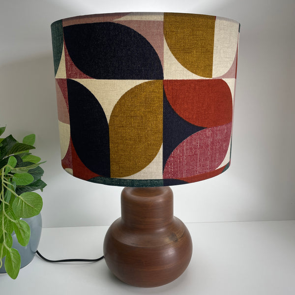 Drum lampshade with Bold and Beautiful fabric on java wood base, lit by shades at grays.