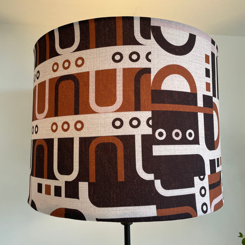 Drum style lamp shade with geometric harmony tan, lit by shades at grays, nz