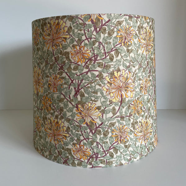 Tapered lampshade featuring a vintage floral pattern with yellow-orange flowers and green leaves on a cream background, with purple stems.
