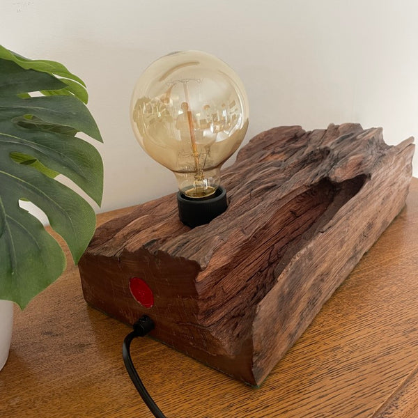 Handcrafted NZ lamp by shades at grays created from reclaimed timber, eroded contours, side view with black lead and makers brand.
