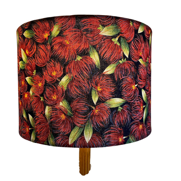 Handcrafted drum lamp shade with pohutukawa fabric, lit on white background.