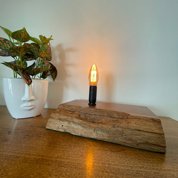 Handcrafted heritage lamp by shades at grays using a reclaimed jarrah beam with additional candle bulb, lit, angled view.