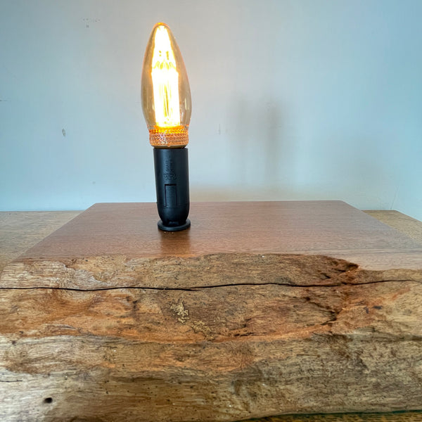 Handcrafted heritage lamp by shades at grays using a reclaimed jarrah beam with additional candle bulb, lit, front view, close  up.
