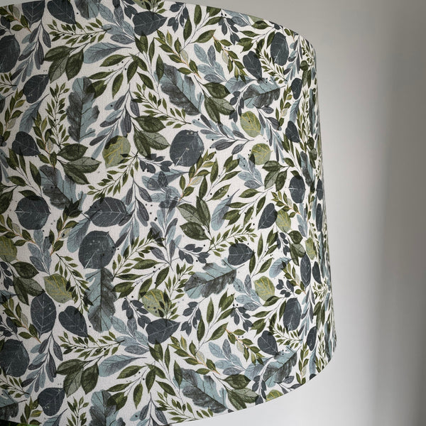 Handcrafted lampshade with Serenity Leaves fabric, close up by shades at grays, unlit.