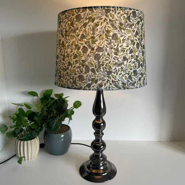 Handcrafted lampshade with Serenity Leaves fabric, tapered 38 shade size, on grey metal stand,by shades at grays, lit.