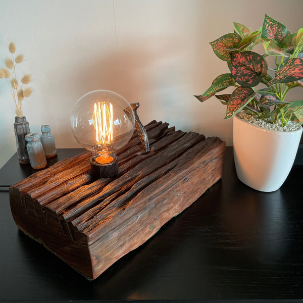 Hand crafted wood lamp created from old railway sleeper with replica edison bulb, lit, top, front and side view showing deep eroded grooves, made by shades at grays.