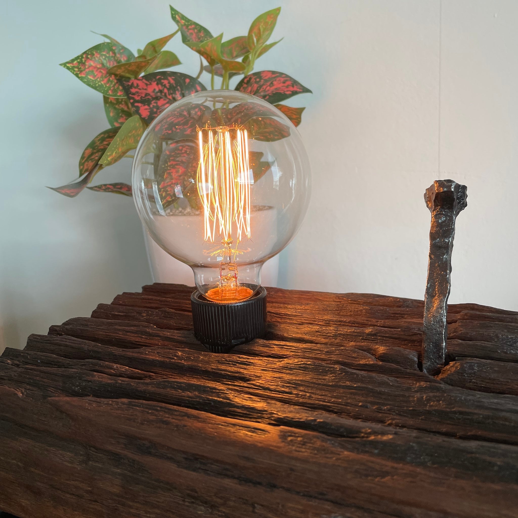 Close up of Hand crafted wood lamp created from old railway sleeper with replica edison bulb, lit, made by shades at grays.