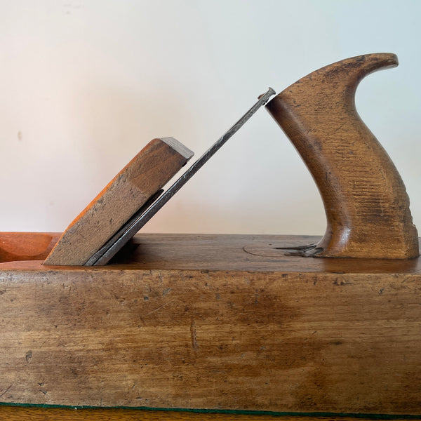 Heritage lamp crafted by shades at grays from original carpenters' half jack plane with replica edison bulb, lit, close up of handle and cutting blade.