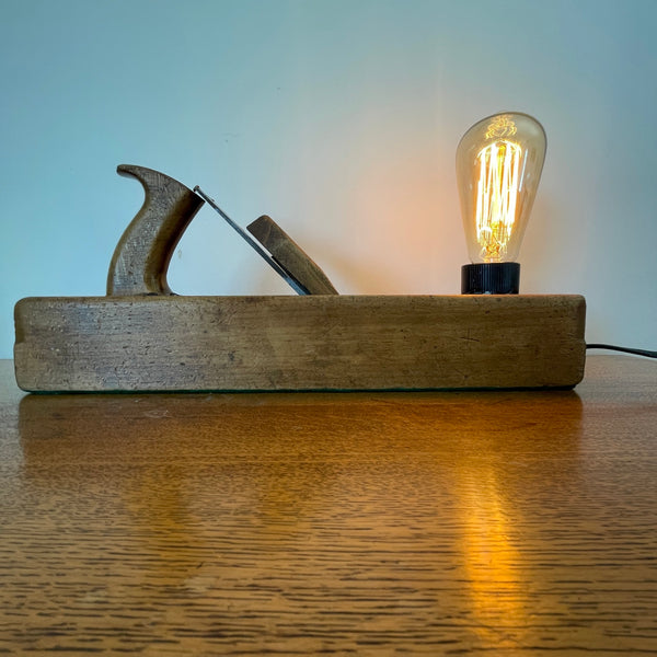 Heritage lamp crafted by shades at grays from original carpenters' half jack plane with replica edison bulb, lit, front view.