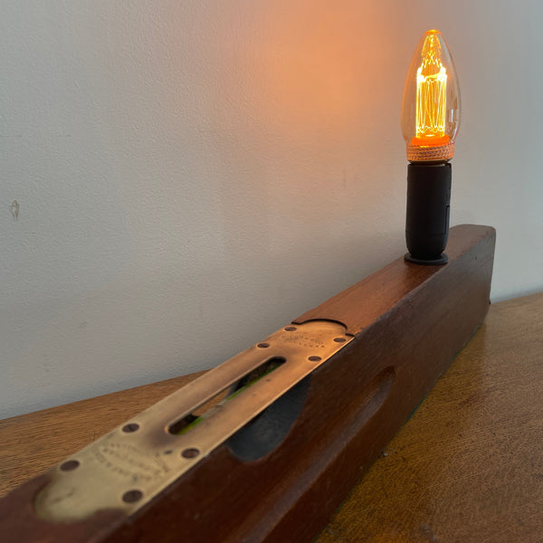 Heritage lamp from long builder's level with added light bulb, lit, side long view, upcycled by shades at grays.