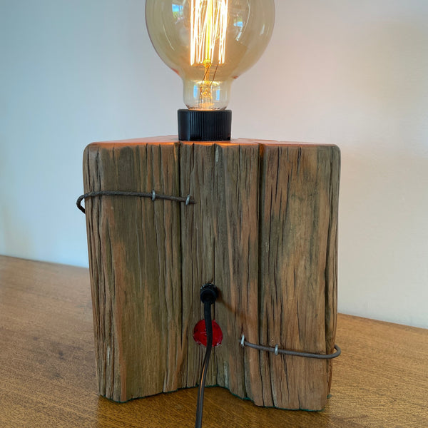 Heritage lamp upcycled from authentic totara post, with original No 8 wire, back view with black lead and makers red brand.