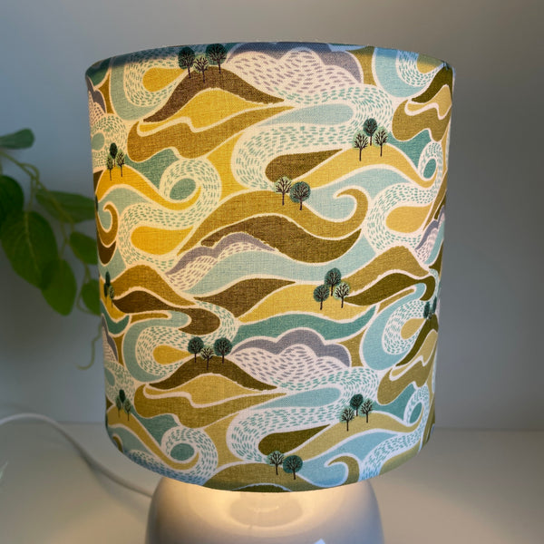 Close up of hills and trees fabric on small table lamp by shades at grays