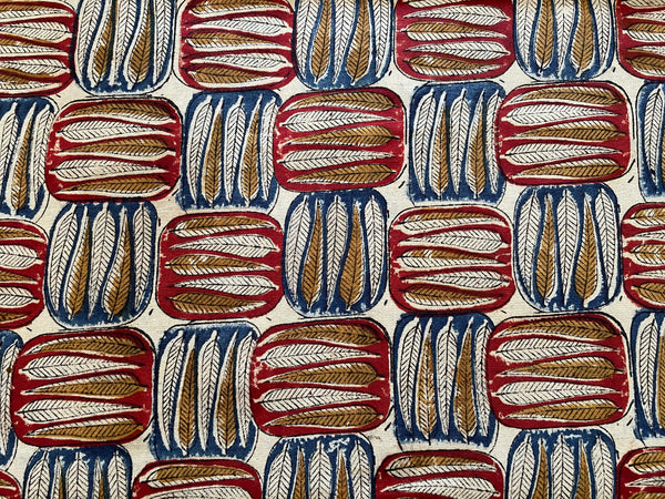 Close up of Block Leaf Spice fabric: slender ochre leaves in alternating brick red and navy blocks on a cream background.