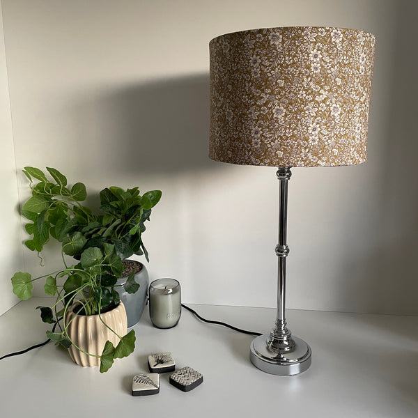 Drum style light shade with manuka sage fabric on silver table lamp, unlit.