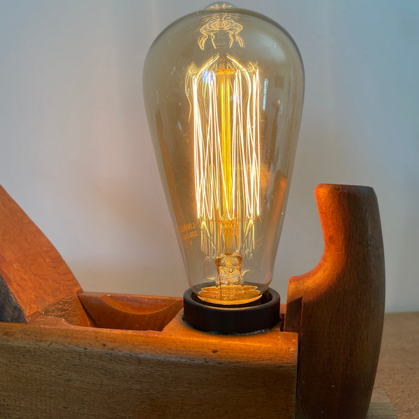 Industrial style table lamp made from a repurposed antique wood plane styled for a home office or bookshelf.