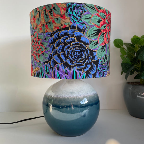 Ceramic blue lamp base with Kaffe Fassett House of Leeks Dark fabric on handcrafted medium drum lamp shade, made in nz by shades of grays.